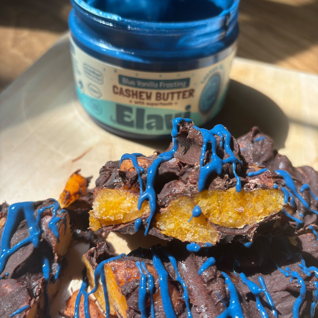Close-up of Fudgey Mandarin Bark with chocolate-covered mandarin slices drizzled in blue cashew butter, jar on wooden board