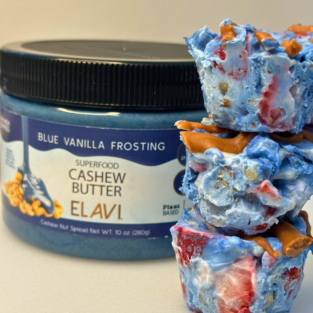 Stack of three tye-dye yogurt parfait bites with blue vanilla yogurt, strawberries, and chocolate drizzle in front of an ELAVI Blue Vanilla Frosting cashew butter jar
