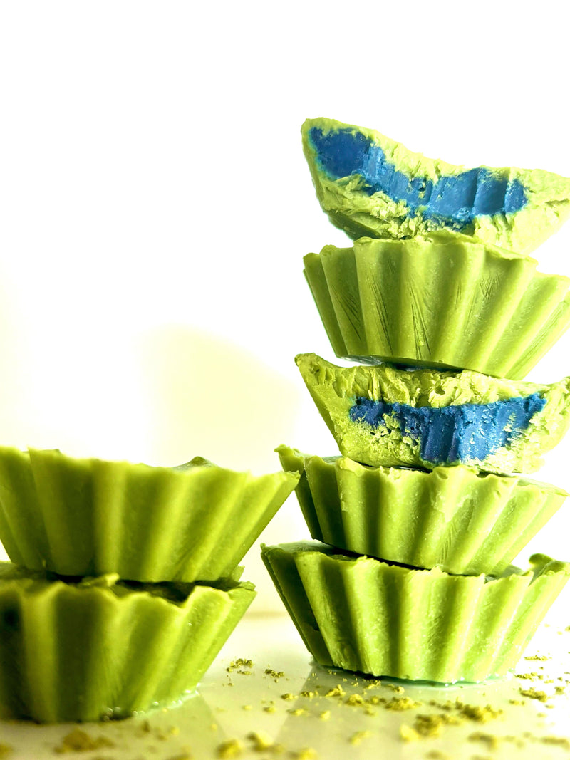 Close up side view of stacked Blue Matcha cashew butter cups showing green matcha shell and bright blue filling on white background