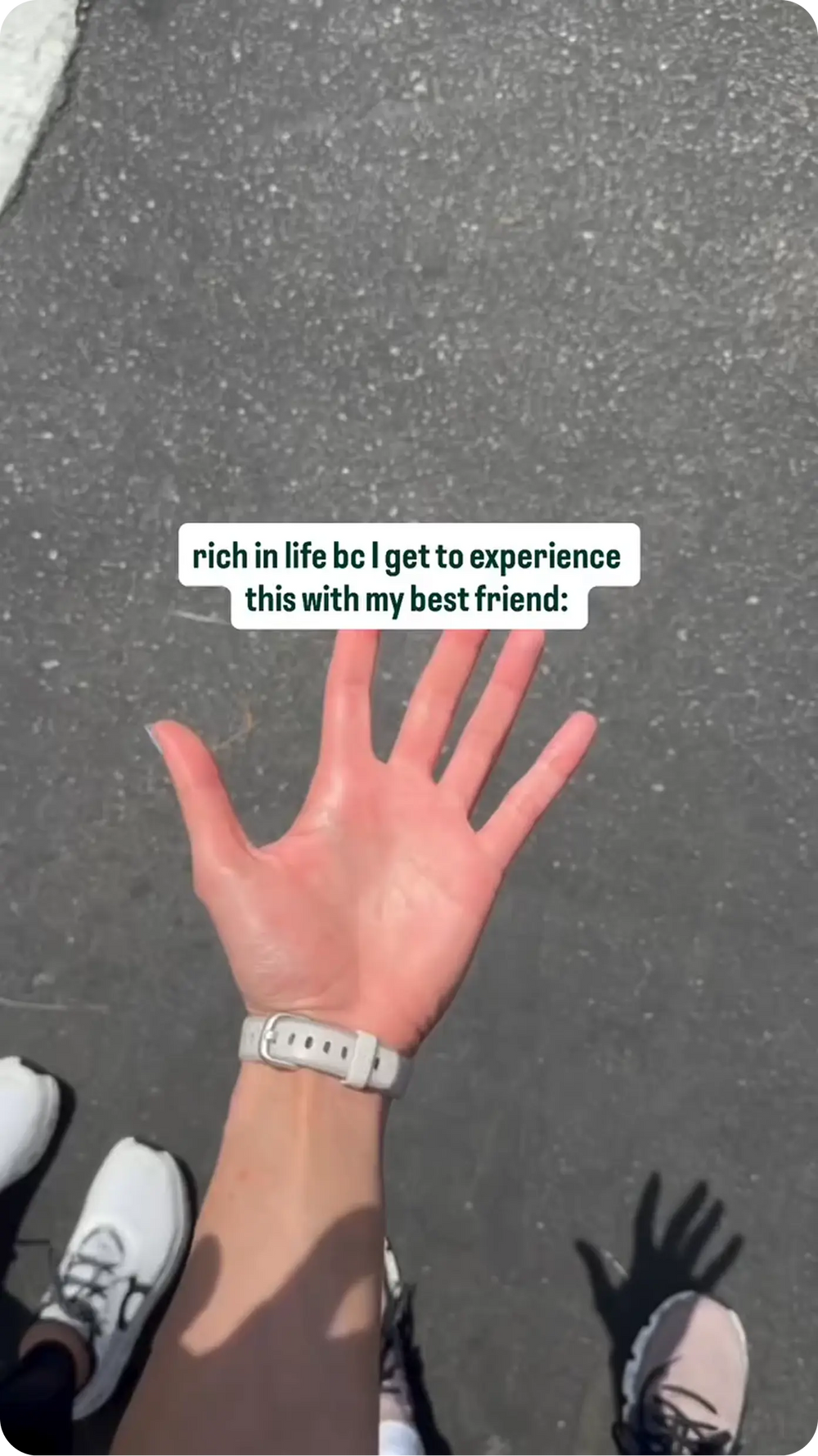 Hand held up walking with a friend on pavement, overlaid text: rich in life bc I get to experience this with my best friend